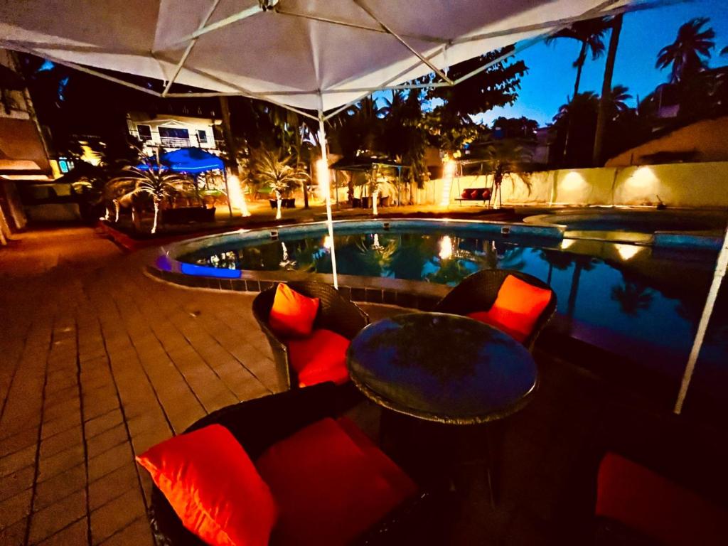 una piscina con sillas, una mesa, una mesa y una tienda de campaña en Shivam Resort With Swimming Pool ,Managed By The Four Season - 1 km from Calangute Beach en Goa