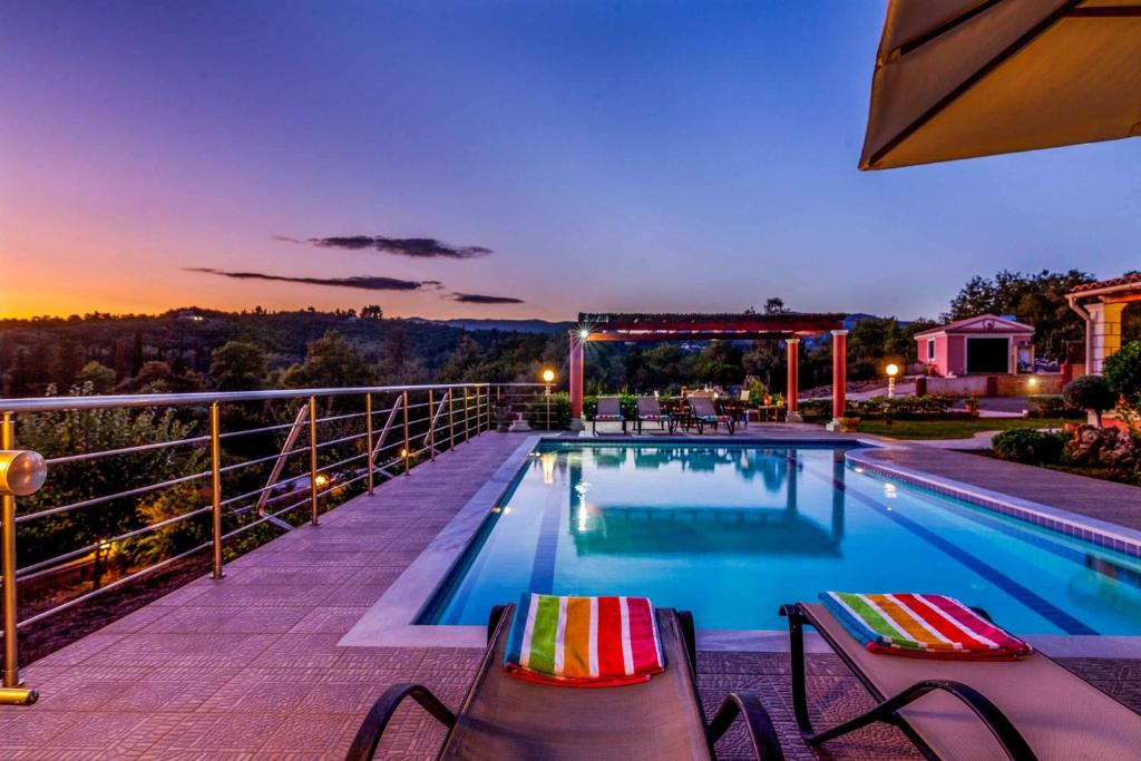 a swimming pool with two chairs on a balcony at Villa Mirela Mikri in Dassia