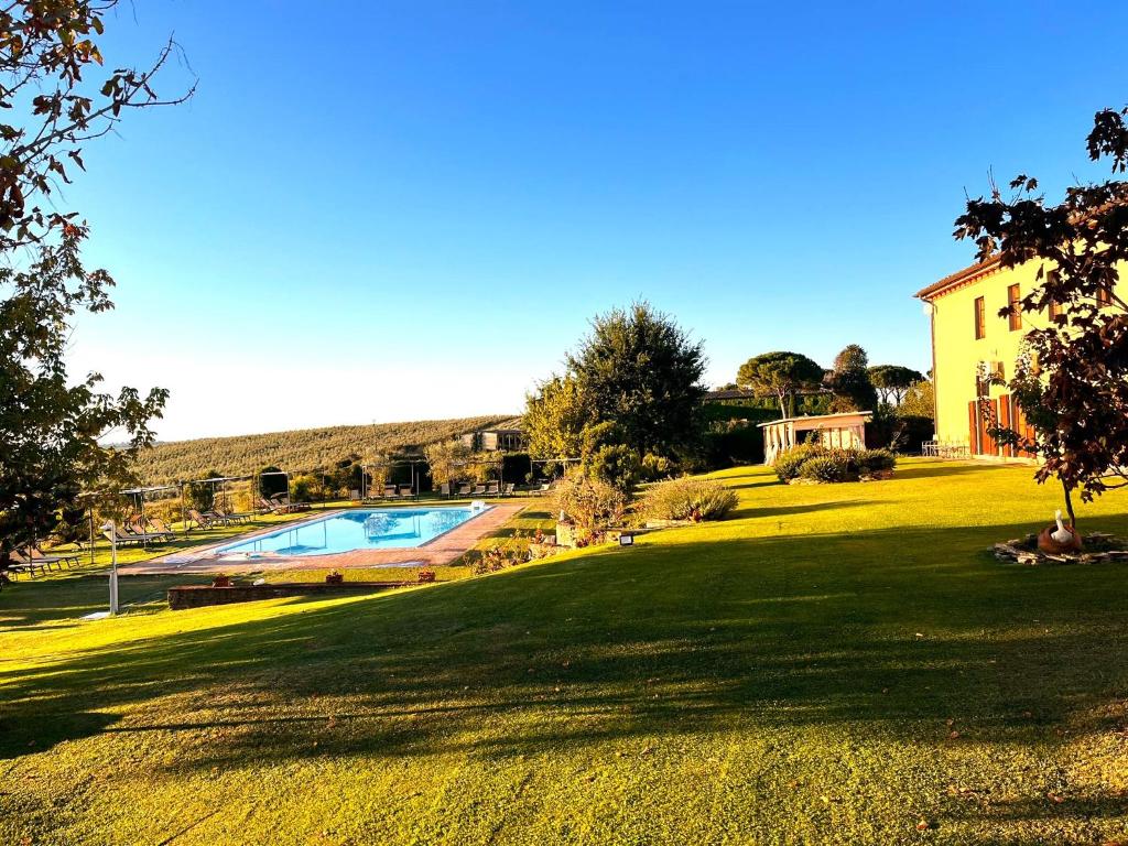 un patio verde con piscina y una casa en Podere Il Belvedere su Cortona, en Castiglion Fiorentino