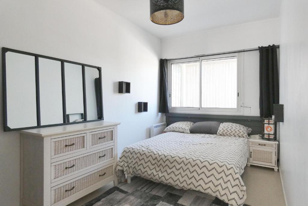 - une chambre avec un lit, une commode et des fenêtres dans l'établissement Les Demoiselles, appartement emplacement idéal, à Saint-Jean-de-Monts