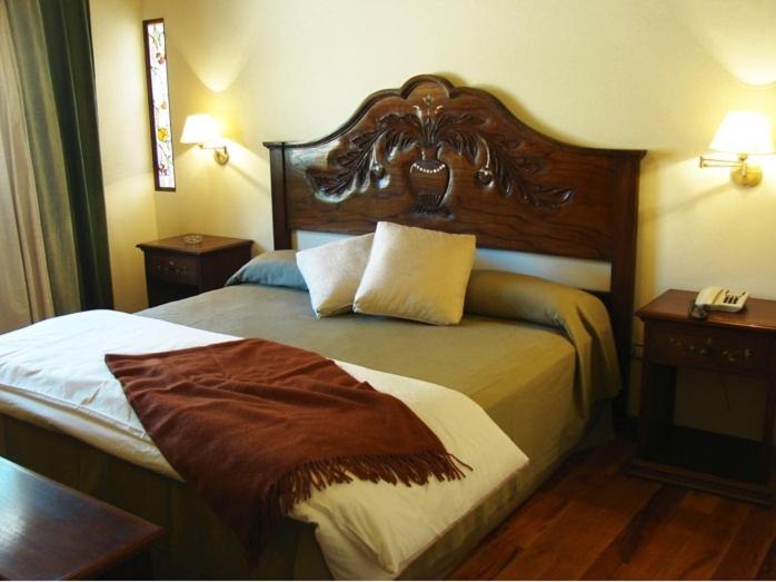 a hotel room with a bed with a wooden headboard at Hotel Marqués De Tojo in Purmamarca