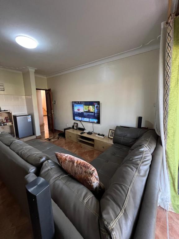sala de estar con sofá de cuero y TV de pantalla plana en MD comfort homes, en Kampala
