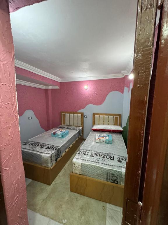 Duas camas num quarto com paredes cor-de-rosa em غرفه خاصه لك جديده وفرش جديد ومميز بها سريرين وتلفزيون em Almançora