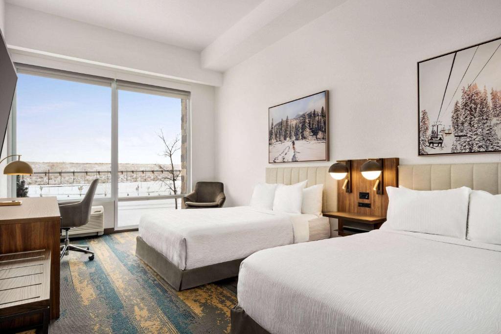 ein Hotelzimmer mit 2 Betten, einem Schreibtisch und einem Fenster in der Unterkunft La Quinta Inn & Suites by Wyndham Denver Parker in Parker