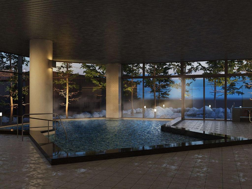 a large swimming pool in a building with a large window at Mercure Urabandai Resort & Spa in Kitashiobara