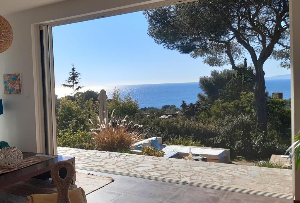 um quarto com uma grande porta de vidro deslizante com vista para o oceano em VILLA ANADINE - Aiguebonne BOULOURIS - PLEINE VUE MER - À 5 minutes à pied de la plage - Climatisée em Saint-Raphaël