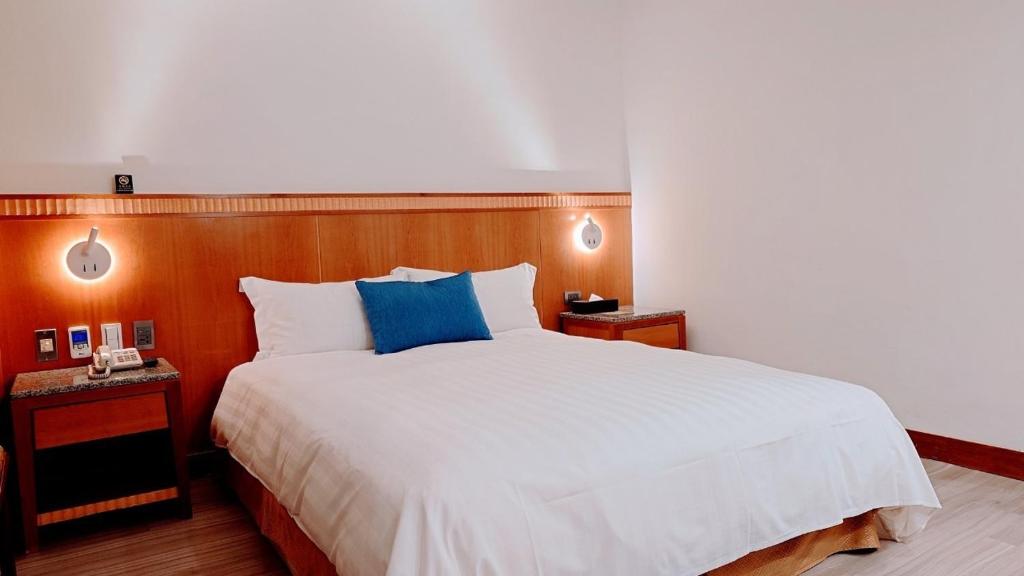 a bedroom with a large bed with a blue pillow at Hub Hotel Kaohsiung Cisian Branch in Kaohsiung