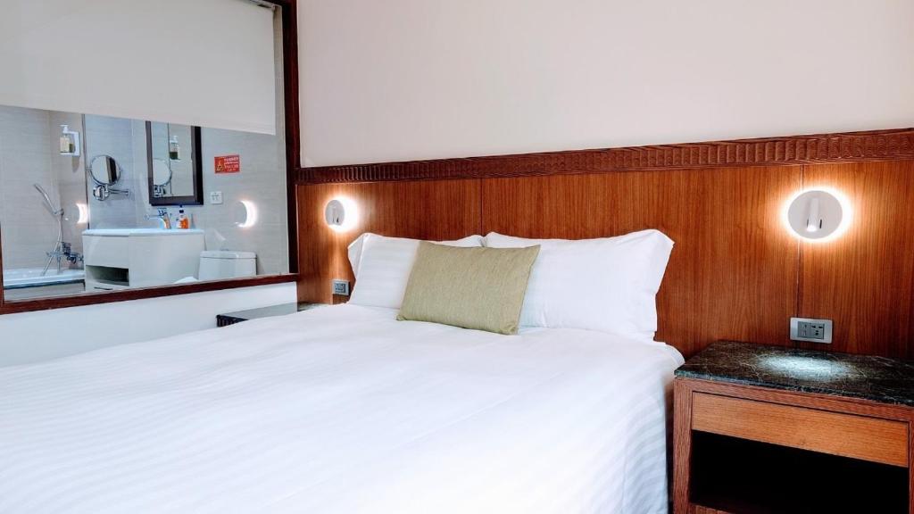 a bedroom with a large white bed and a bathroom at Hub Hotel Kaohsiung Cisian Branch in Kaohsiung