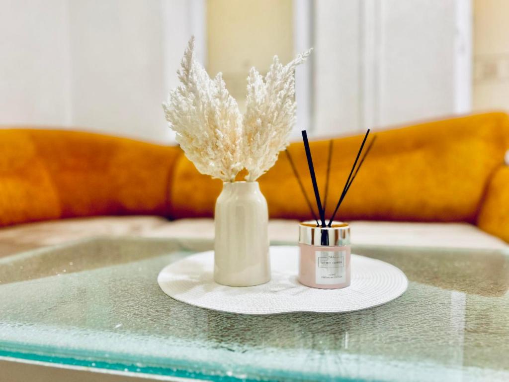 Una mesa con un jarrón blanco y una vela encima. en Ezero apartamentai, en Šiauliai