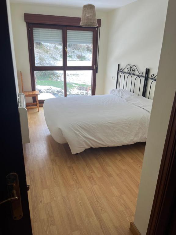 um quarto com uma cama branca e uma janela em Apartamentos Fele2 em Felechosa