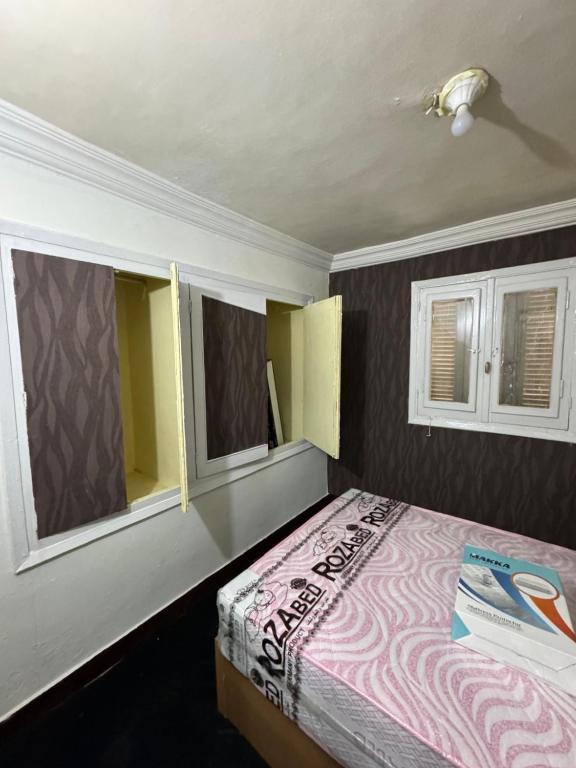 a bedroom with a bed and two windows at شقه صغيره فندقيه في موقع مميز جديده وفرش وموبيليا جديده in Mansoura