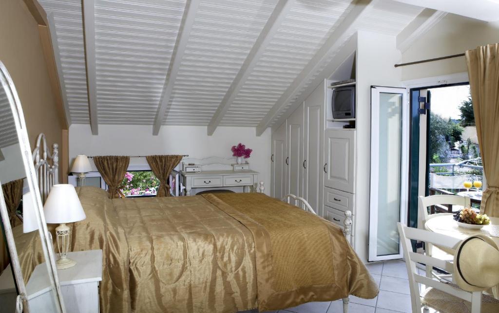 a bedroom with a bed and a table and a window at Dafnoudi Hotel Apartments in Fiskardo