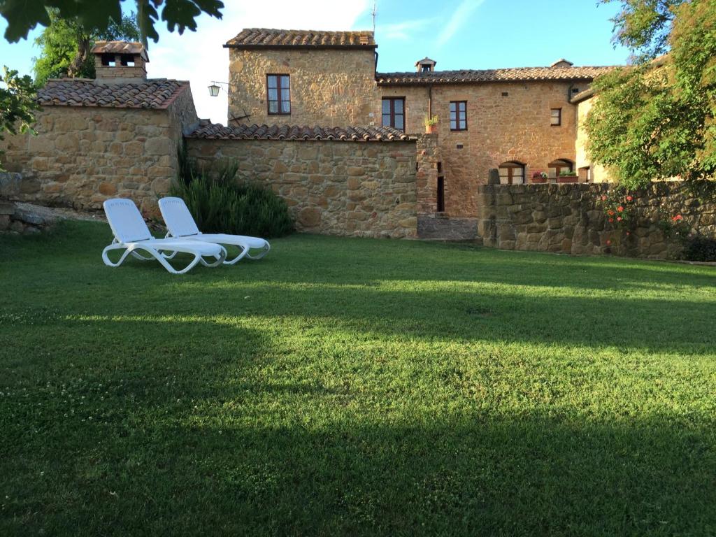 two white chairs sitting on a lawn in front of a house at Villa Fonte all'Oppio con area piscina recintata in Pienza