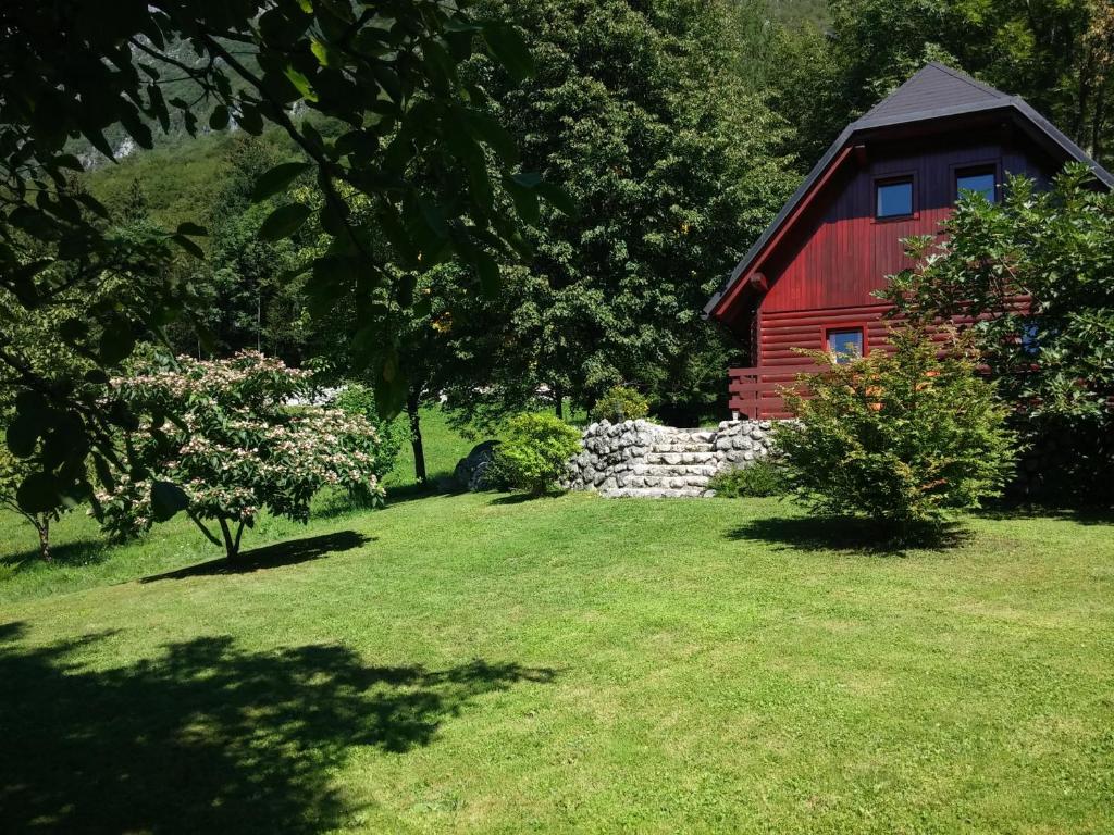 a red barn with a stone wall in a yard at Apartma Brin Bovec in Bovec