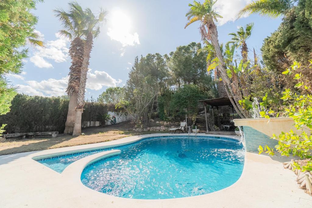 a swimming pool in a yard with palm trees at La Torre: casa perfecta con piscina privada in Pobla de Montornés