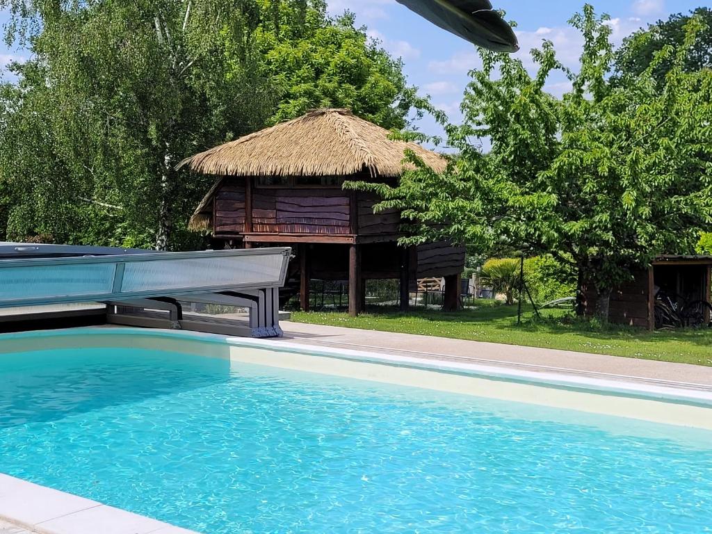 a resort with a swimming pool and a hut at La paillote idyllique in Faverolles-sur-Cher