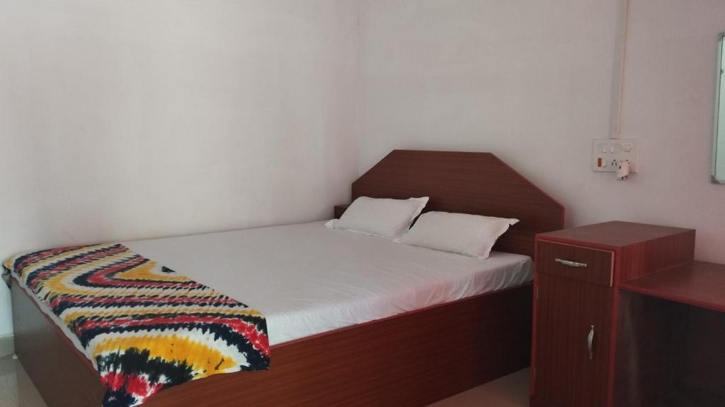 um pequeno quarto com uma cama e uma cabeceira em madeira em Blue Whale Resort and Restaurant em Neil Island