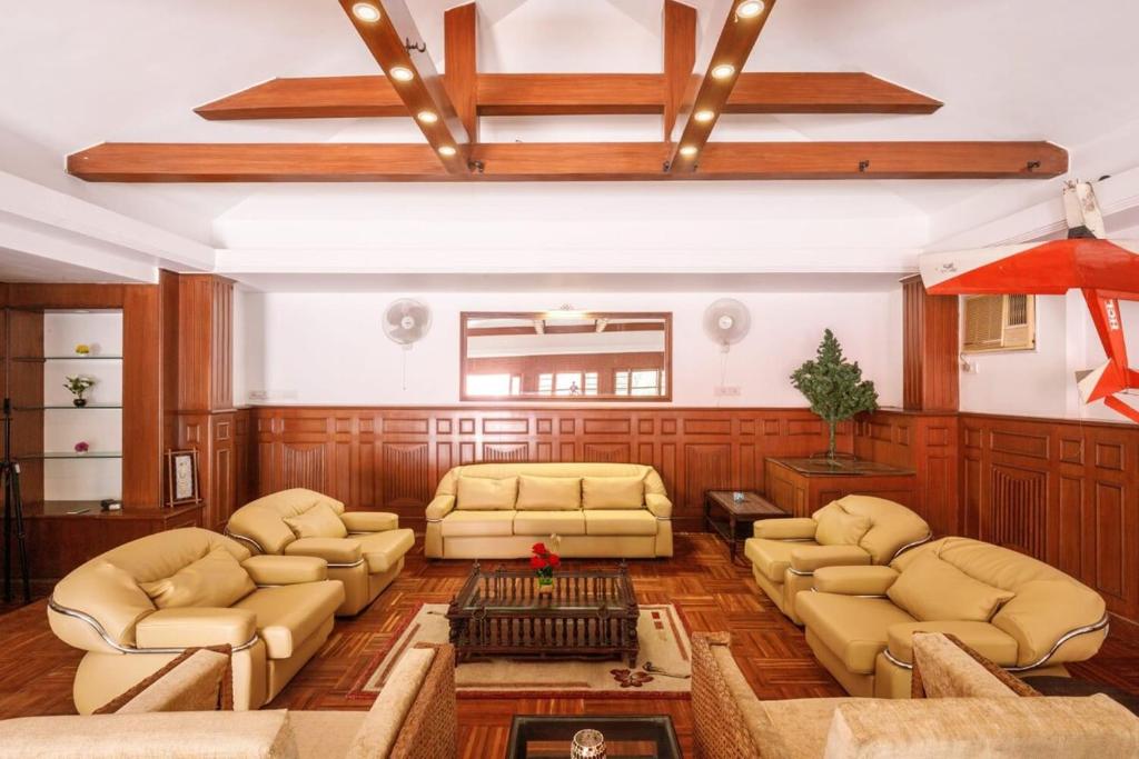een grote woonkamer met banken en een plafond bij Woodstone Manor by JadeCaps Penthouse Indiranagar in Bangalore