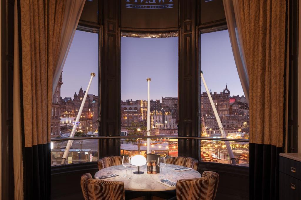 a table with chairs in a room with a large window at Hotel Indigo - Edinburgh - Princes Street by IHG in Edinburgh