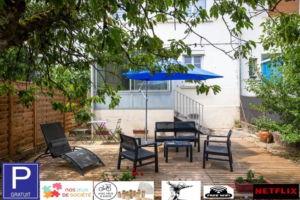 un patio con sillas y una sombrilla azul en Le coquet chez Maguy Maison de ville avec jardin en Besanzón