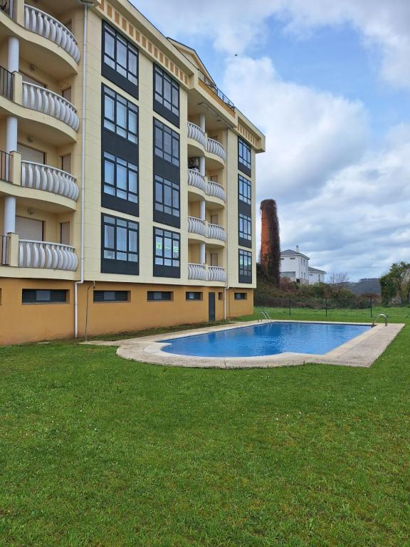 un edificio de apartamentos con piscina frente a él en Paseo Costa Vicedo, en O Vicedo