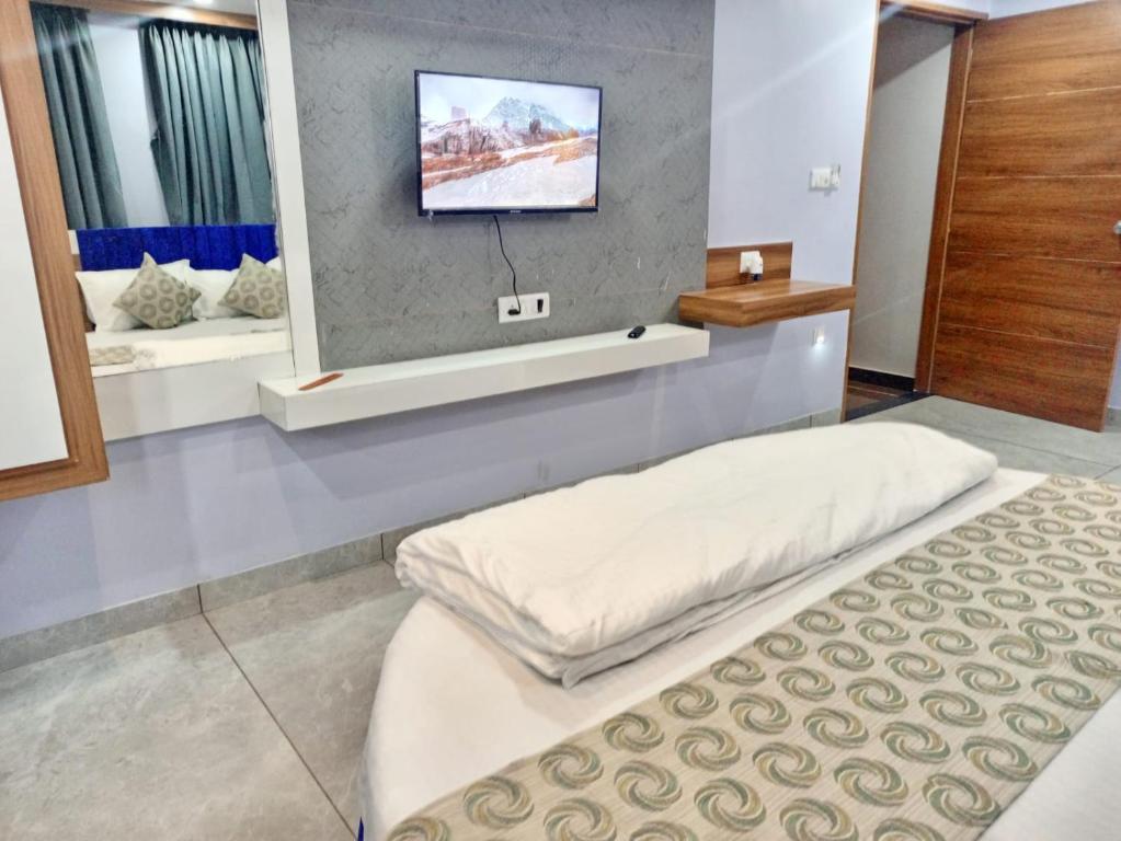 Hotel Red Blue,Ahmedabad في Naroda: غرفة بسريرين وتلفزيون على الحائط