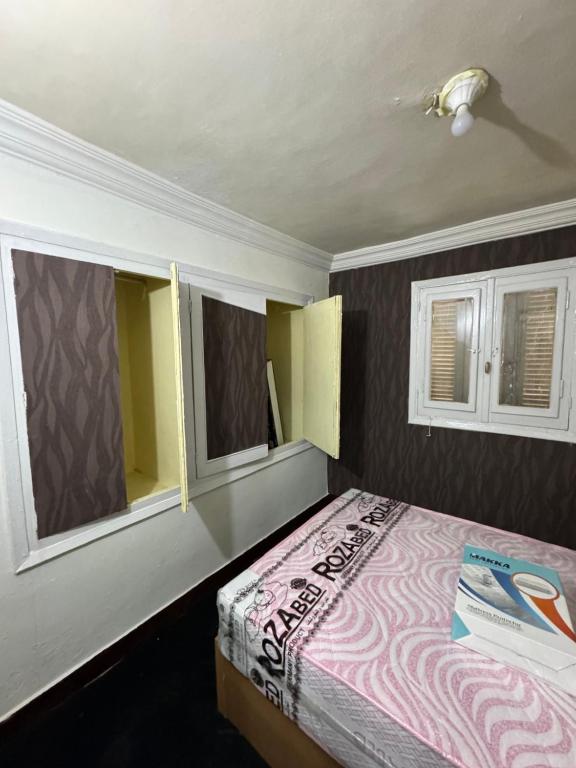 a bedroom with a bed and two windows at شقه غرفتين جديده وعفش جديد وفرش جديد in Mansoura