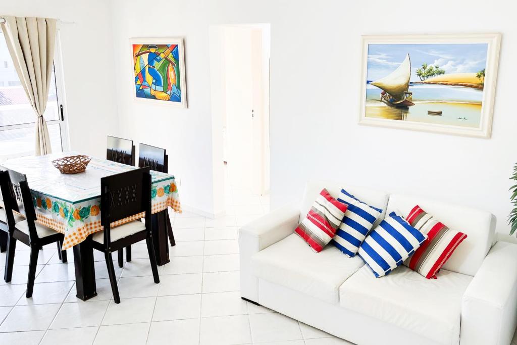 a white living room with a table and a white couch at PS5: Aproveite Ubatuba! Apto Completo & Bem Localizado in Ubatuba