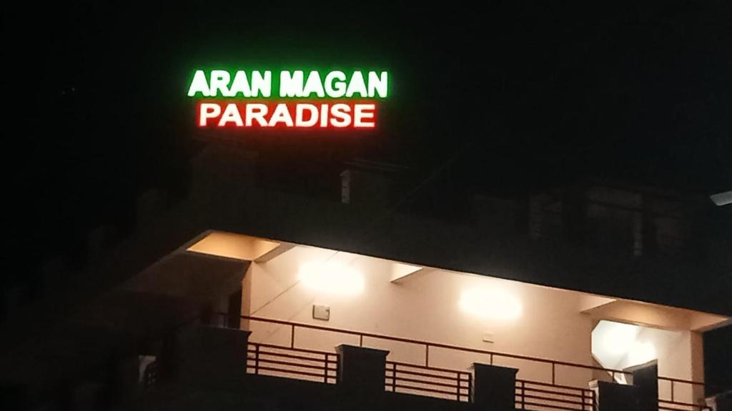 a green sign on top of a building at night at Aranmagan Paradise in Thiruchendur