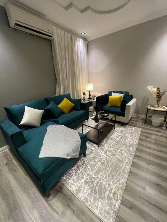 - un salon avec un canapé bleu et des oreillers jaunes dans l'établissement شقة بالملقا بدخول ذاتي, à Riyad