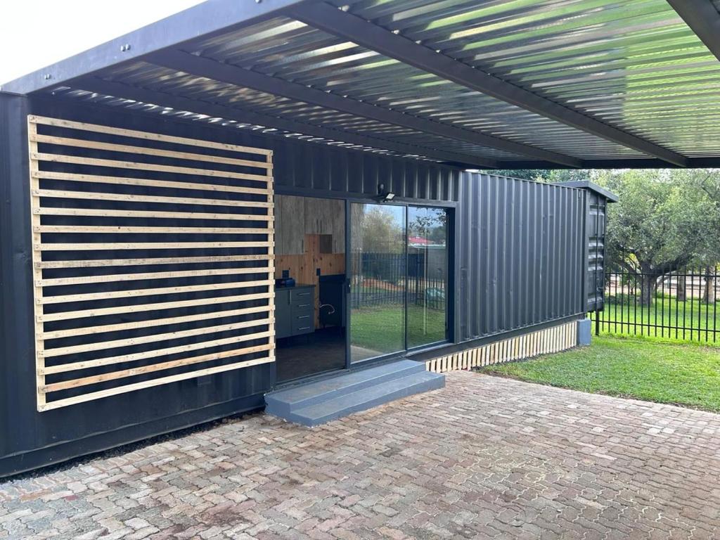 a black building with awning and a patio at Hagedis Dorp - 1 Bedroom Apartment in Hartbeespoort