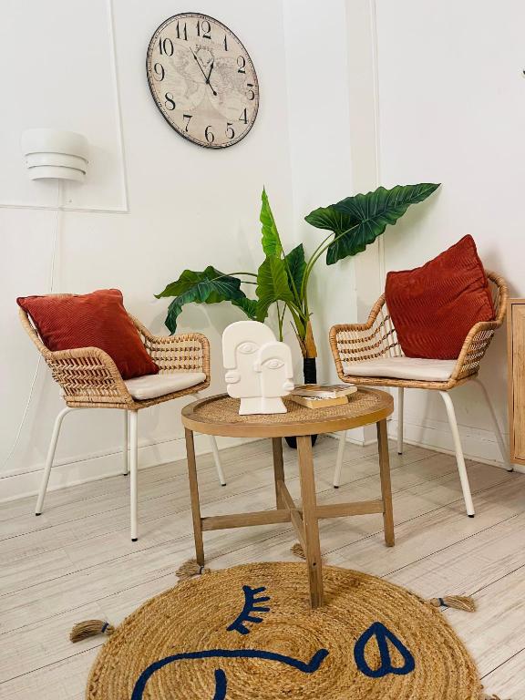 a living room with a table and two chairs and a clock at Studio récemment rénové proche gare et ville in Nice