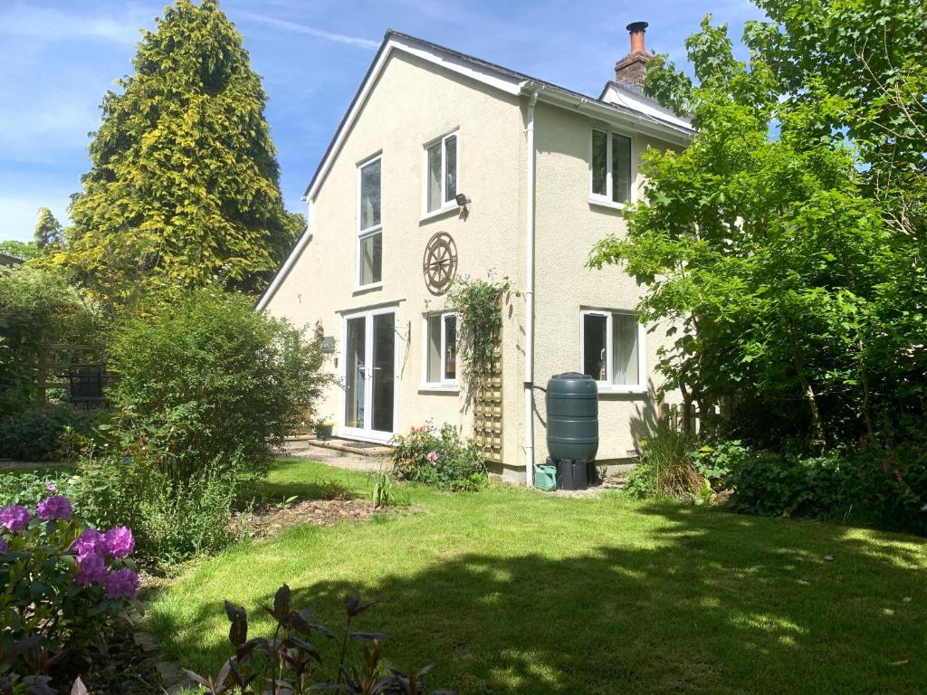 ein weißes Haus mit einer Uhr daneben. in der Unterkunft Sandpipers Cottage - Devon Sleeps 4, Garden, rural, Dog friendly in Holsworthy