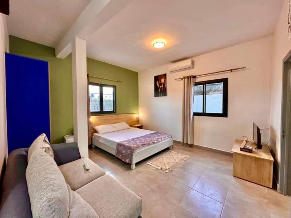 uma sala de estar com uma cama e um sofá em AUBERGE DU NORD em Mitsamiouli