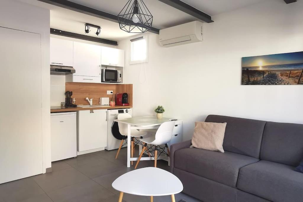 un salon avec un canapé et une table et une cuisine dans l'établissement Le Lumineux l Clim l Parking l Terrasse l Paisible, à Istres