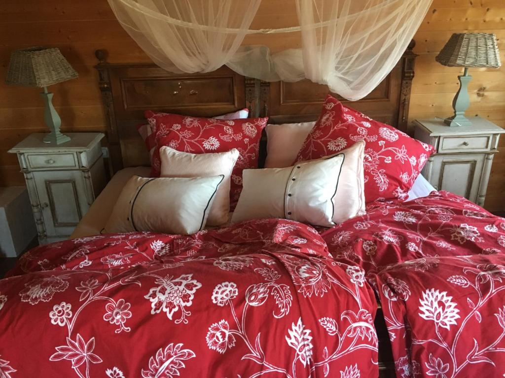 a bed with a red comforter and pillows at Ferien Haus am Feldgarten für 2 bis 9 Personen in Raubling
