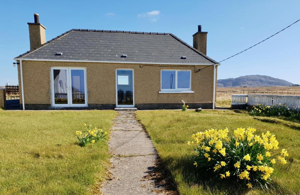 a small house with yellow flowers in the yard at Bayview 1-Bed Cottage in Isle of Lewis in Bragor