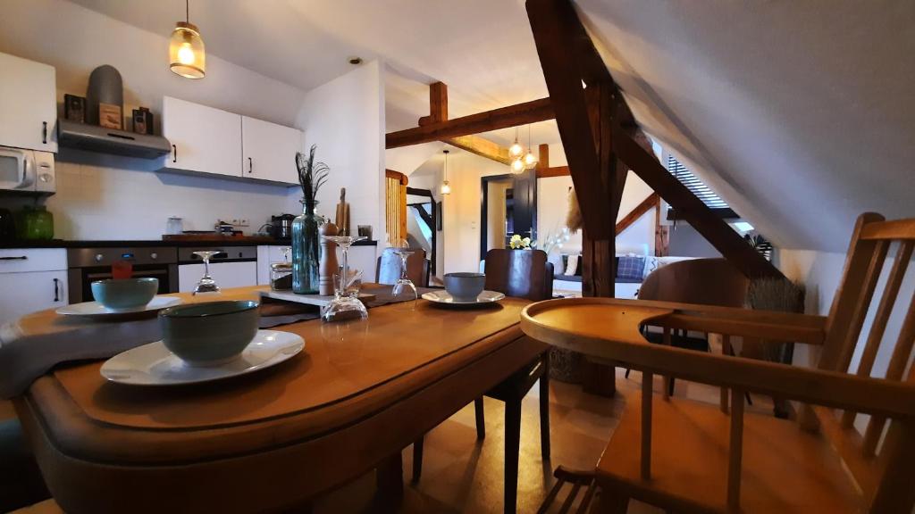 una mesa de madera con platos y cuencos en la cocina en Charmant Appartement proche Strasbourg à Eckwersheim en Eckwersheim