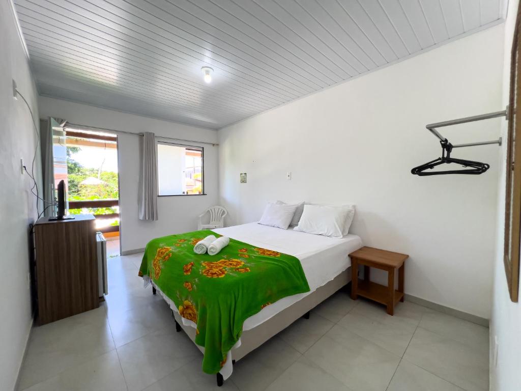 a bedroom with a bed with a green blanket on it at Pousada Praia da Cueira in Cayru