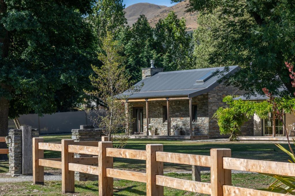 una casa de piedra con una valla delante en Stone Cottage, en Arrowtown