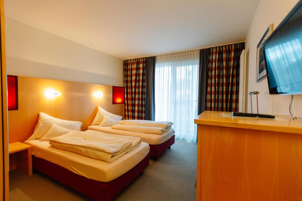 a hotel room with two beds and a flat screen tv at Landhotel Gasthof Drexler GbR in Fürstenfeldbruck