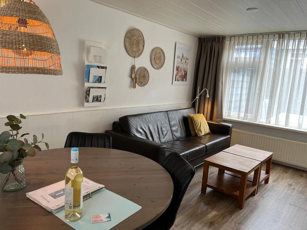 een woonkamer met een zwarte leren bank en een tafel bij Zomerhuis Beach EnJoy in Egmond aan Zee