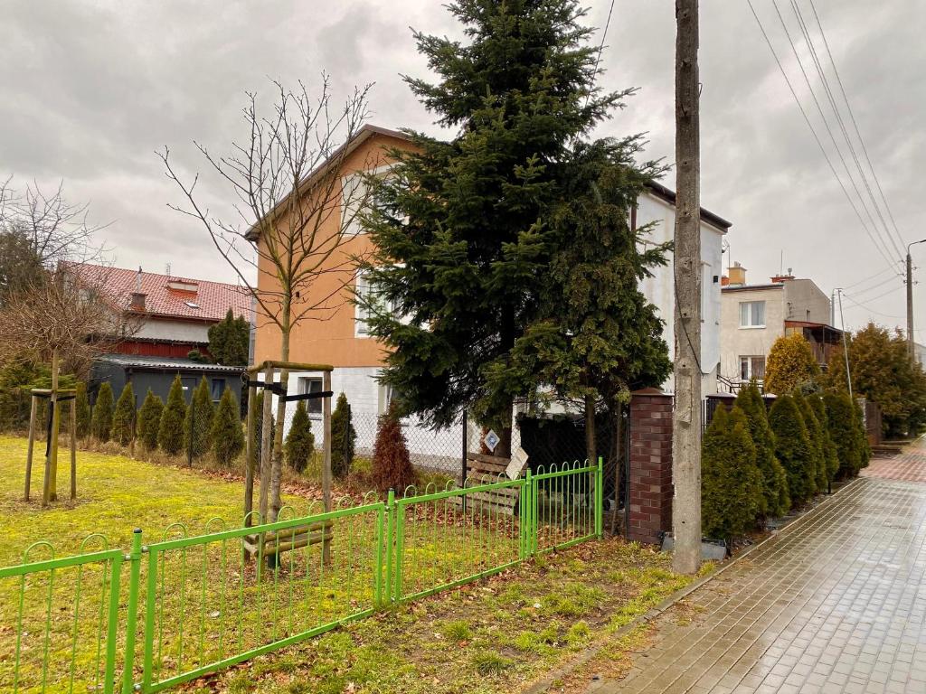 una recinzione verde di fronte a una casa con un albero di Hostel szopena lotnisko a Varsavia