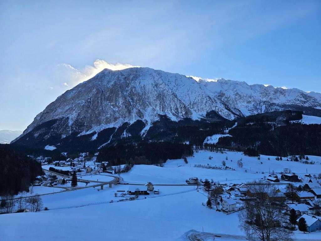 una montaña cubierta de nieve con un pueblo en primer plano en Grimming view Apartment, en Tauplitz