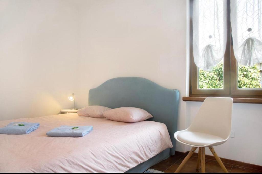 a bedroom with a bed with two pillows and a chair at Terrassen Wohnung Bacio del Sole in Maccagno Inferiore