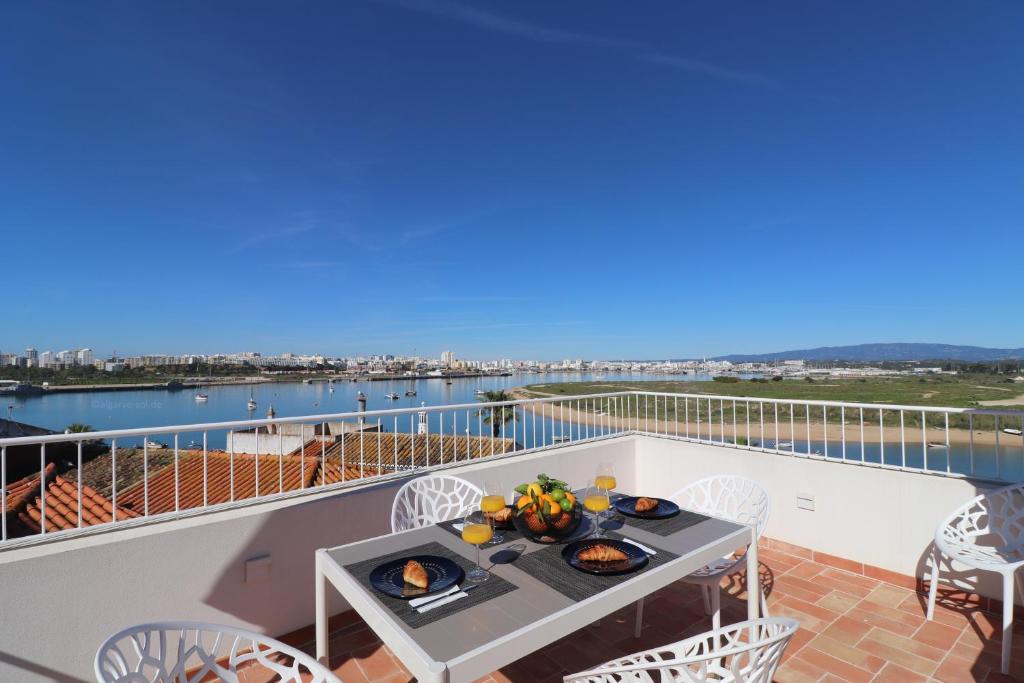 a table on a balcony with a view of the water at Casa Herzog in Ferragudo