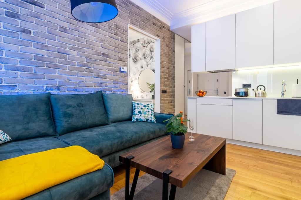 a living room with a blue couch and a brick wall at Apartament Na Deptaku in Lublin