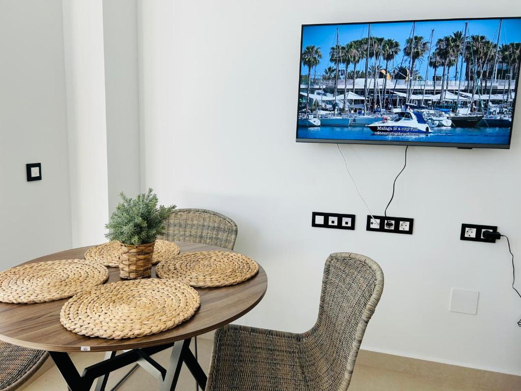 mesa de comedor con sillas y TV en la pared en Victoria Beach Premium, en Málaga