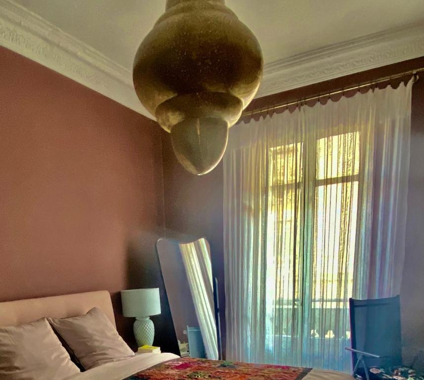 um quarto com uma cama e uma luz pendurada no tecto em Apartment close to the beach - 3 min walk em Nice