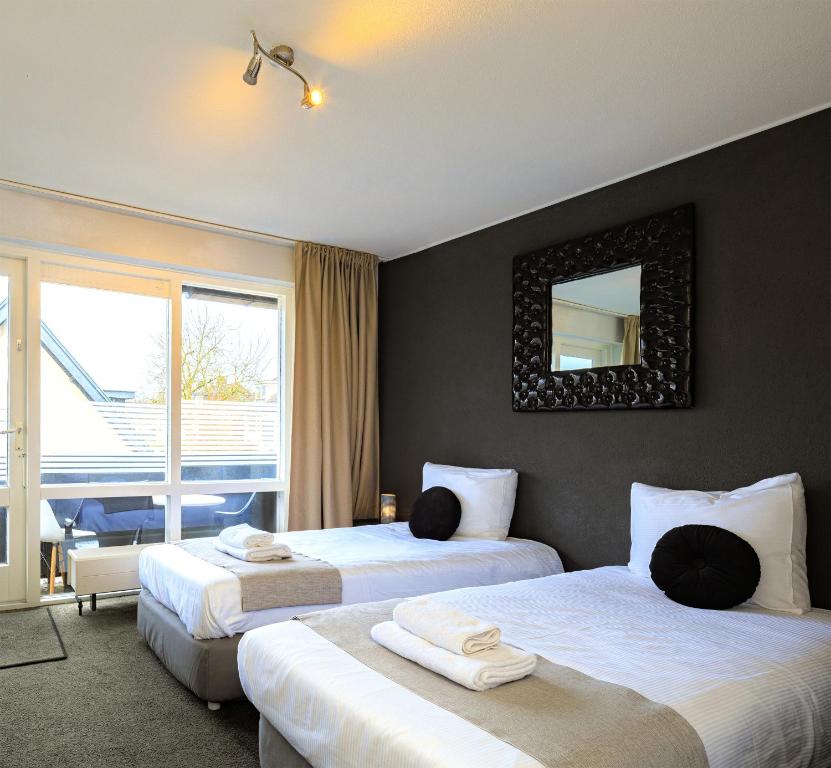 a hotel room with two beds and a mirror at Hotel Berg en Bos in Apeldoorn